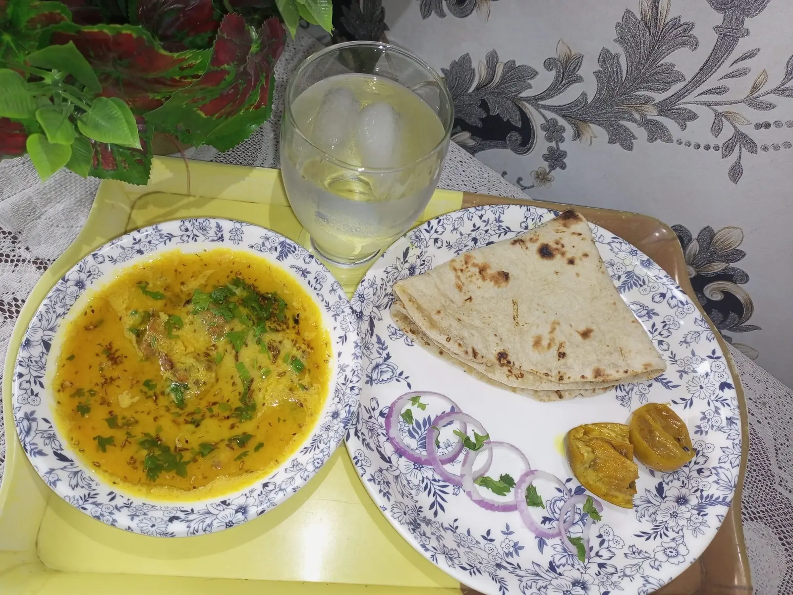 A bowl of dal beside chapati and sliced onion.